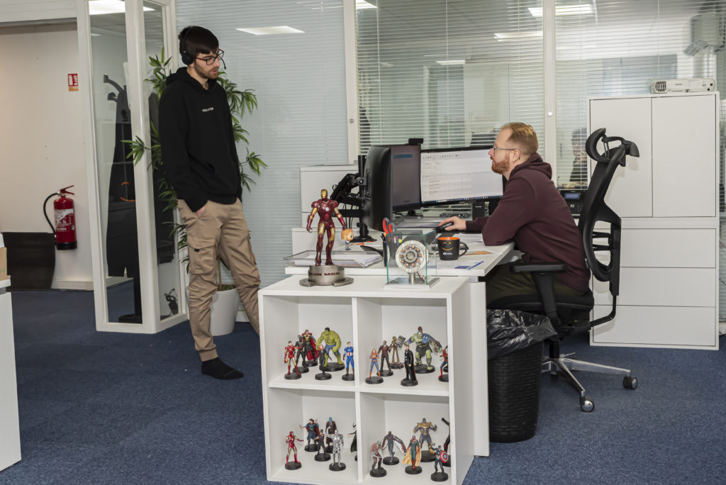 Scène de travail en entreprise IT montrant deux techniciens échangeant dans un bureau moderne, illustrant la collaboration et le management humain chez VIT-S.