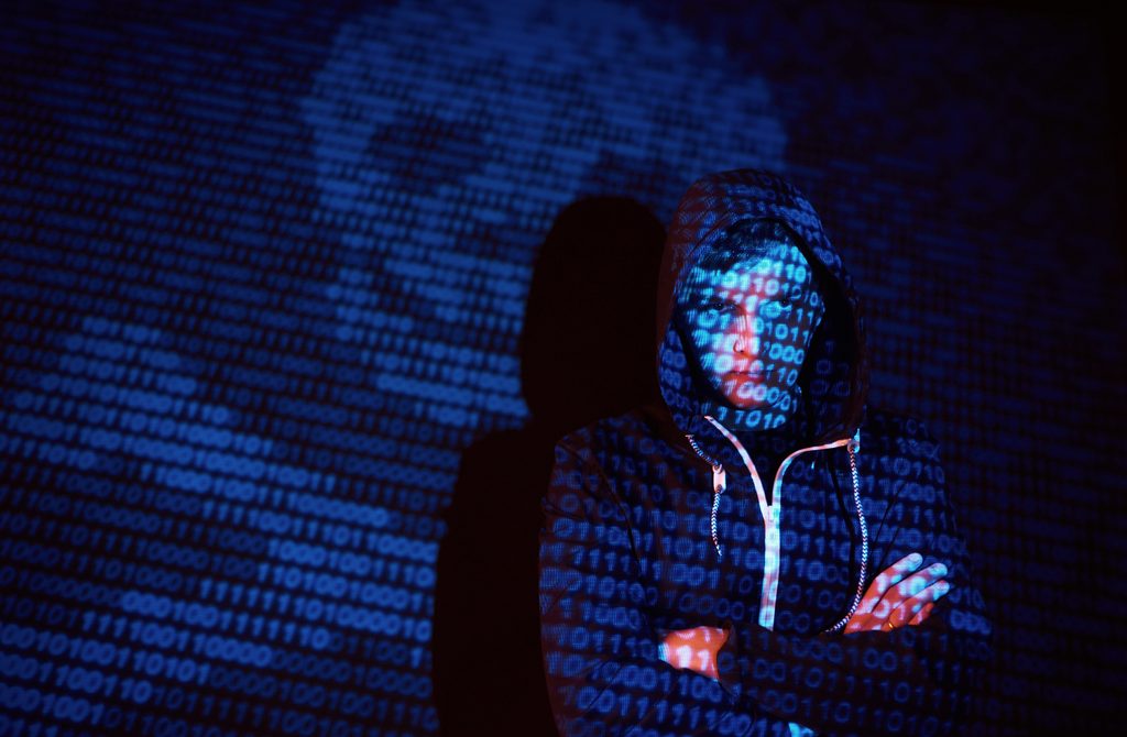 Illustration d’une cyberattaque avec un hacker entouré de code informatique.